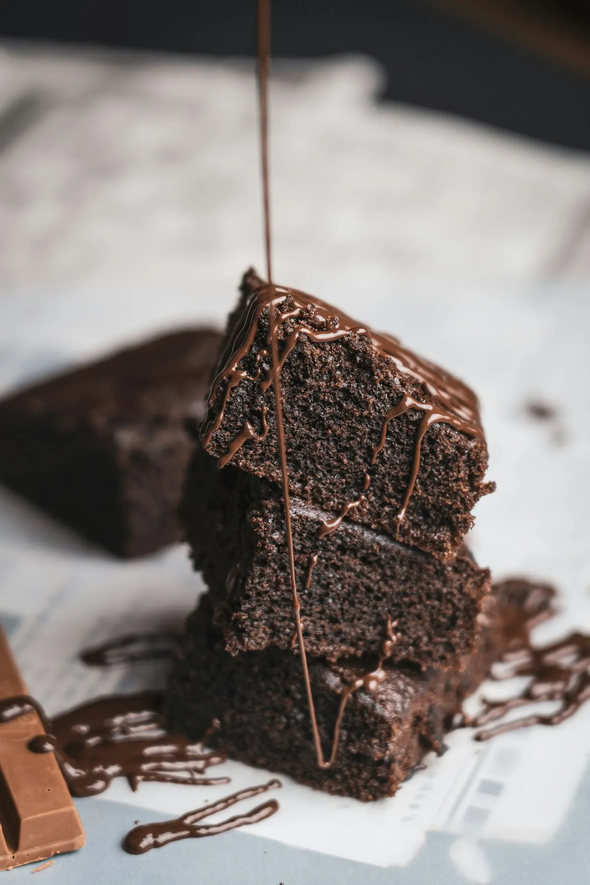 A stack of fudgy craeve brownies with melted chocolate drizzle